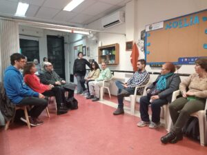 Sentados en ronda socios, amigos y familiares de Noelia Baillo conversan. La placa conmemorativa se ve al centro de la imagen colocada en la pared tras la ronda.